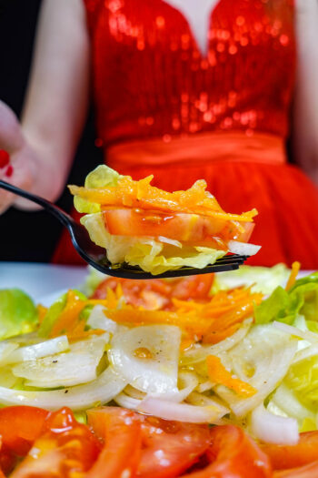 Helena is holding a fork with Portuguese Mixed Salad Salada Mista over the big white plate.