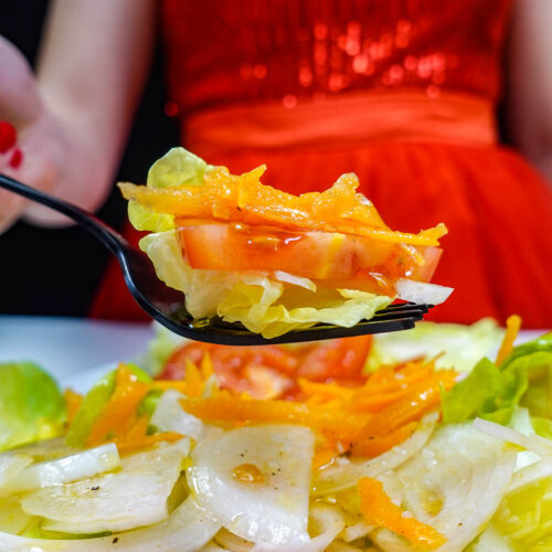 Helena is holding a fork with Portuguese Mixed Salad Salada Mista over the big white plate.