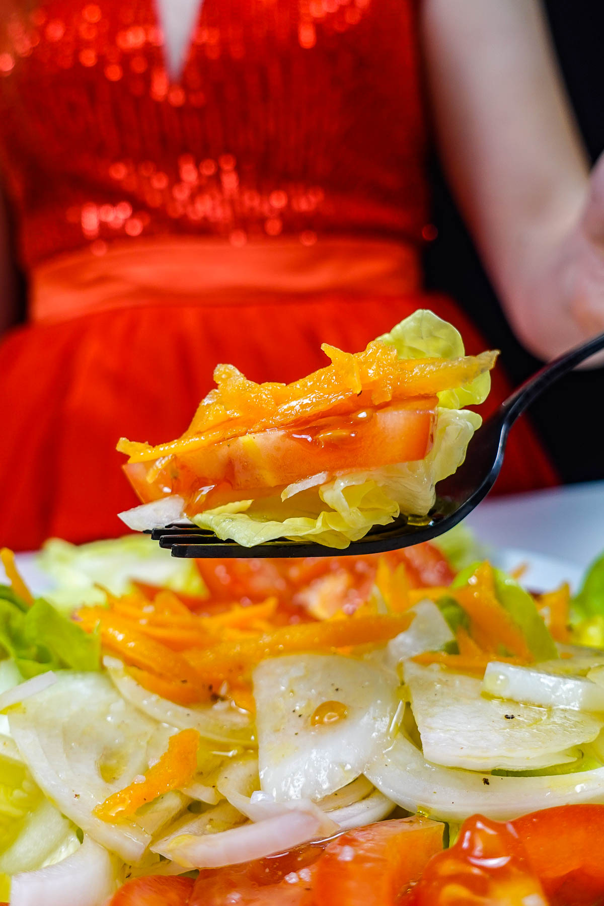 Helena is holding a fork of delicious Portuguese Salada Mista over the seasoned onion.