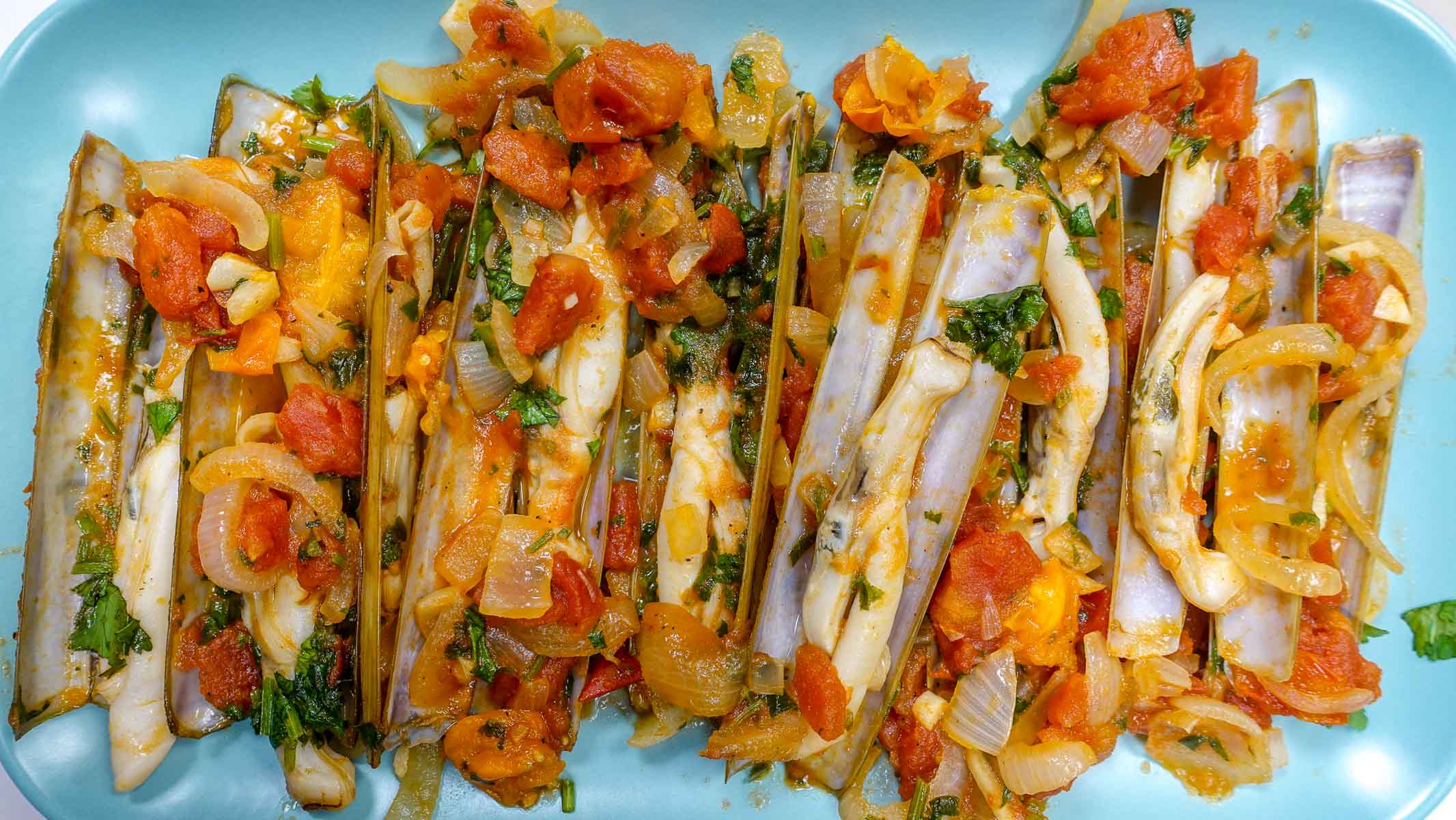 A plate with razor clams in tomato sauce