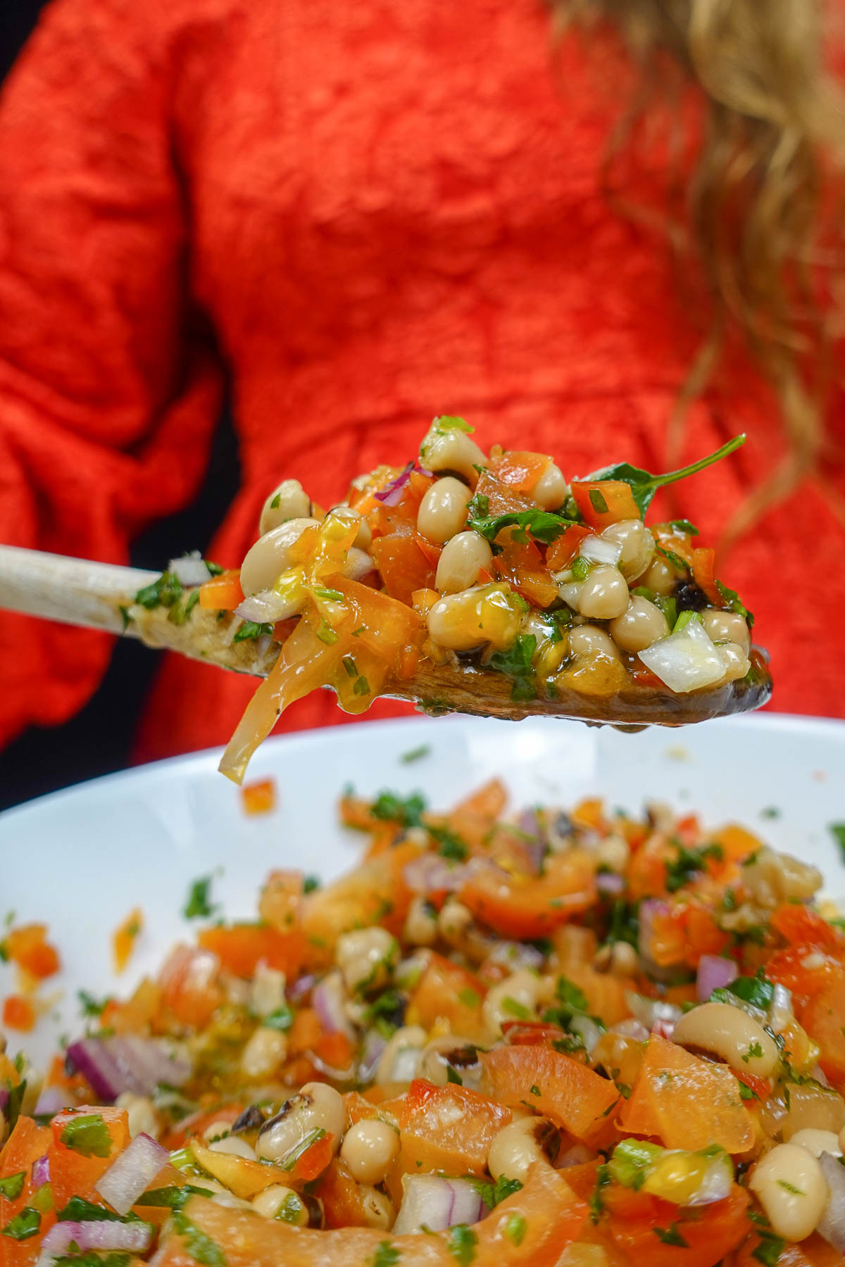 Helena is holding a spoon with Portuguese Black Eyed Pea Salad.