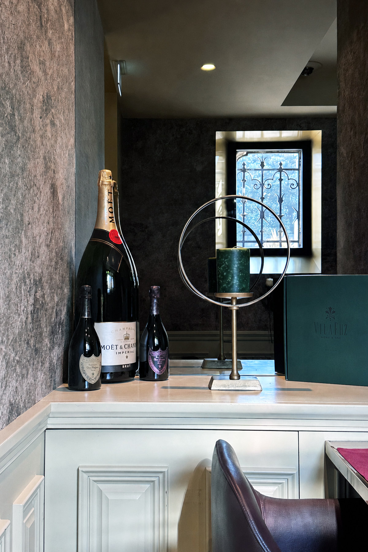 Large and small champagne bottles displayed on a hotel counter.