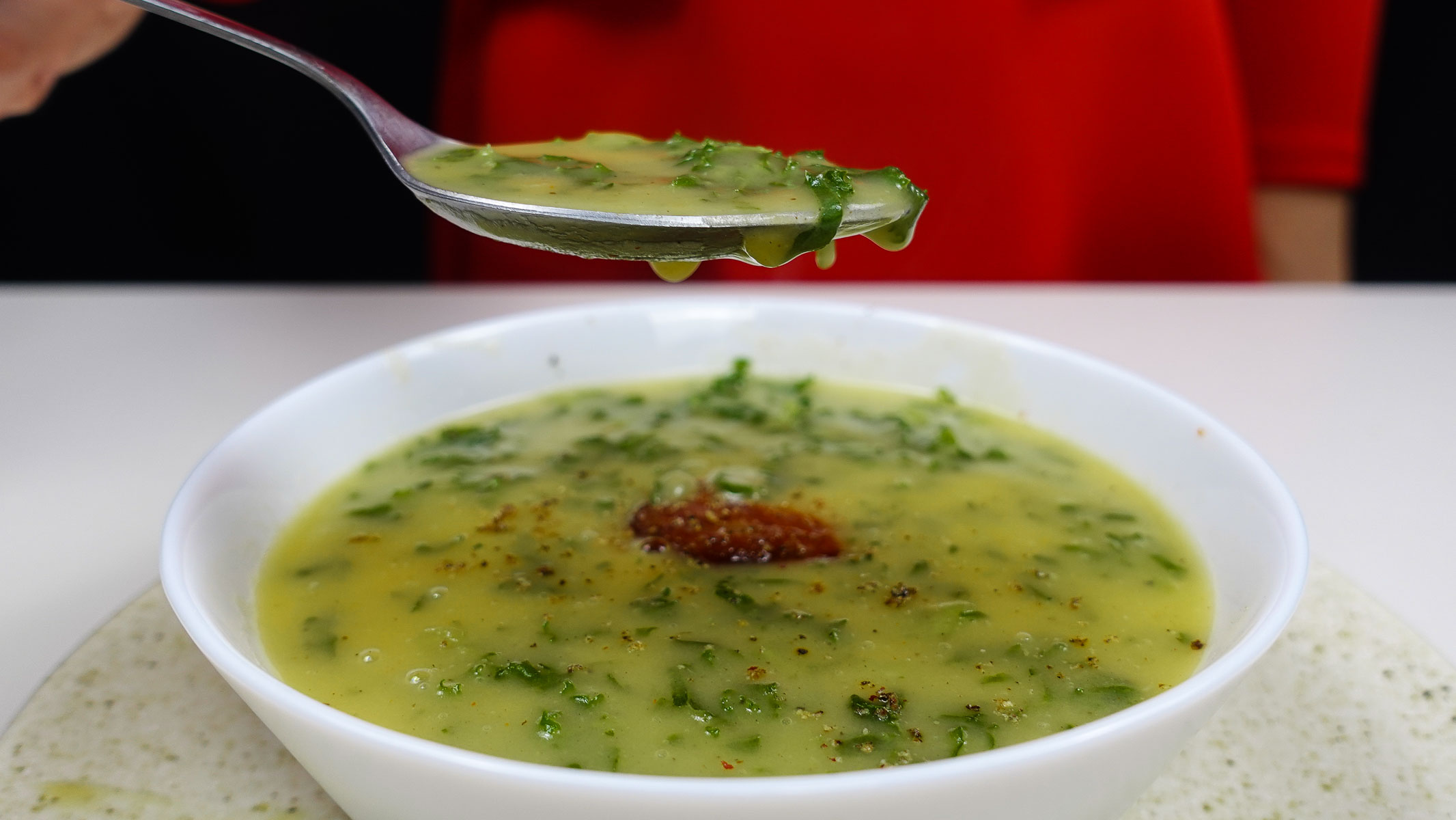 Bowl of creamy Portuguese potato kale soup with spoonful lifted.
