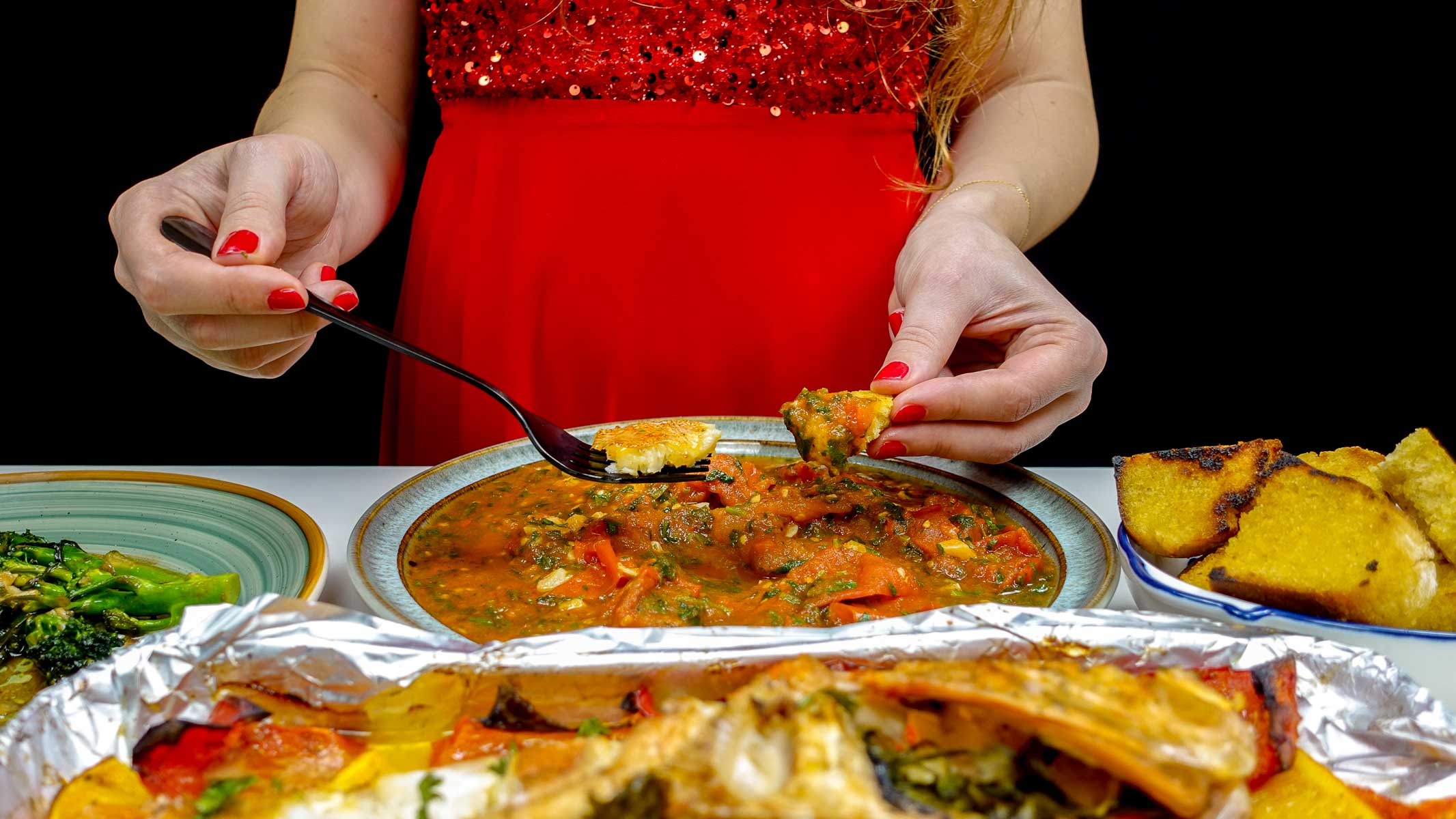 Helena dipping bread into spicy tomato sauce with cilantro on plate.