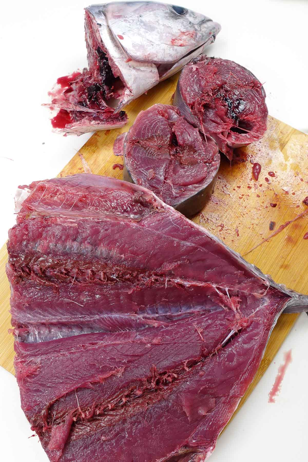 Freshly cut raw tuna fish pieces on a wooden cutting board.