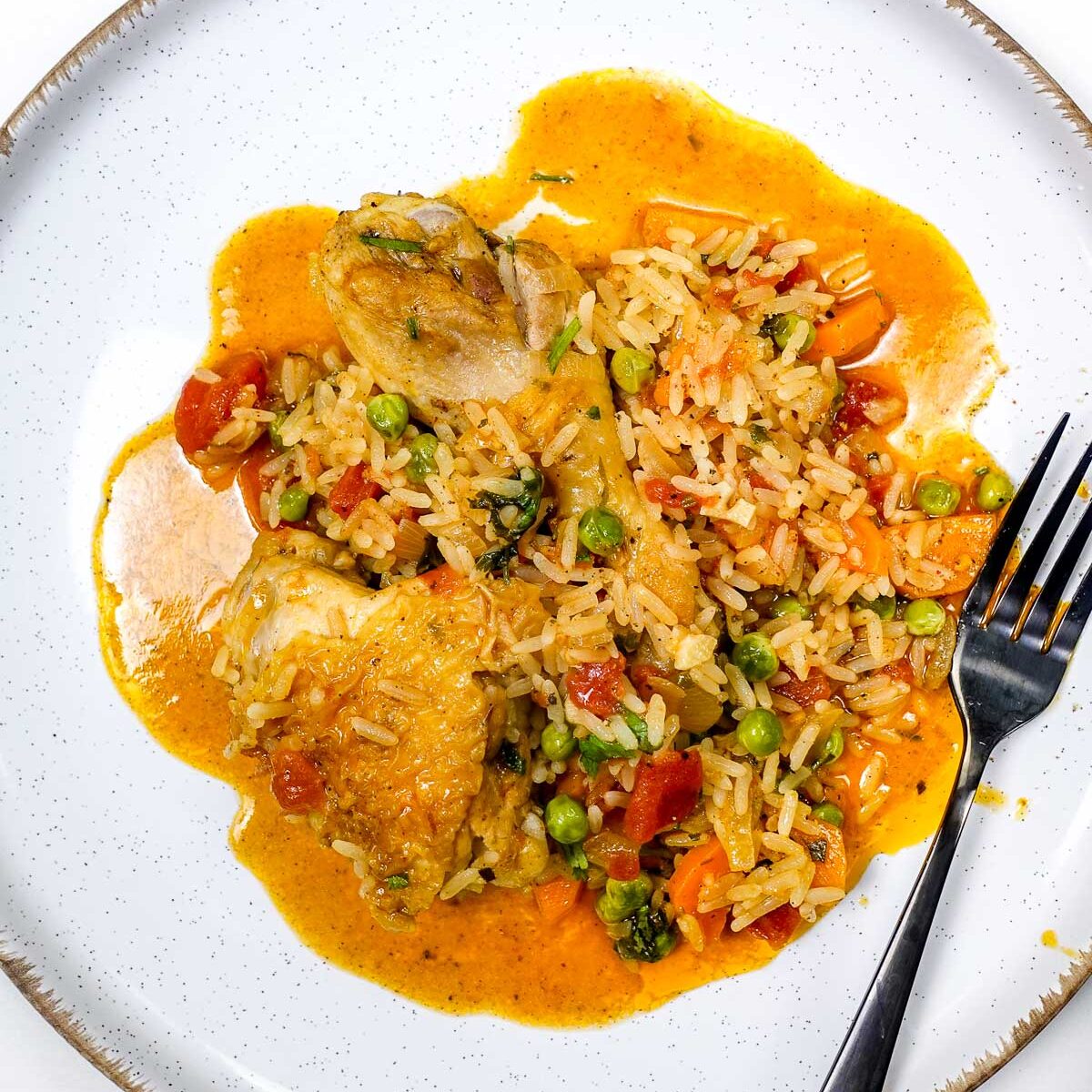 Portuguese chicken rice with peas, carrots, and tomato sauce on white plate.
