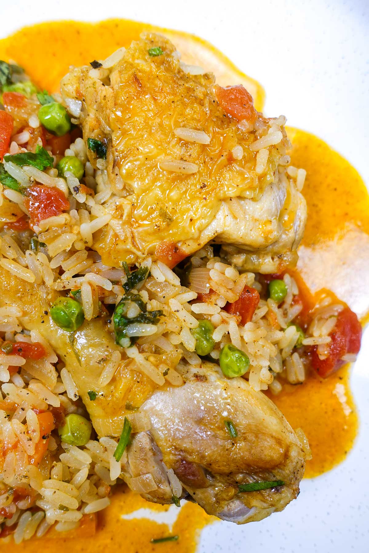 Portuguese chicken with seasoned rice and peas on a white plate.