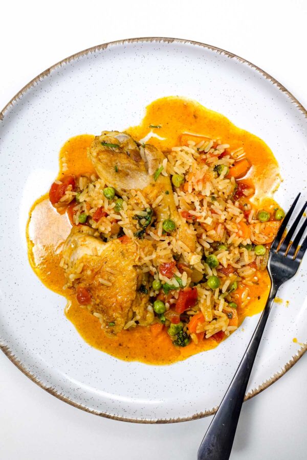 Portuguese chicken rice with peas, carrots, and tomato sauce on white plate.