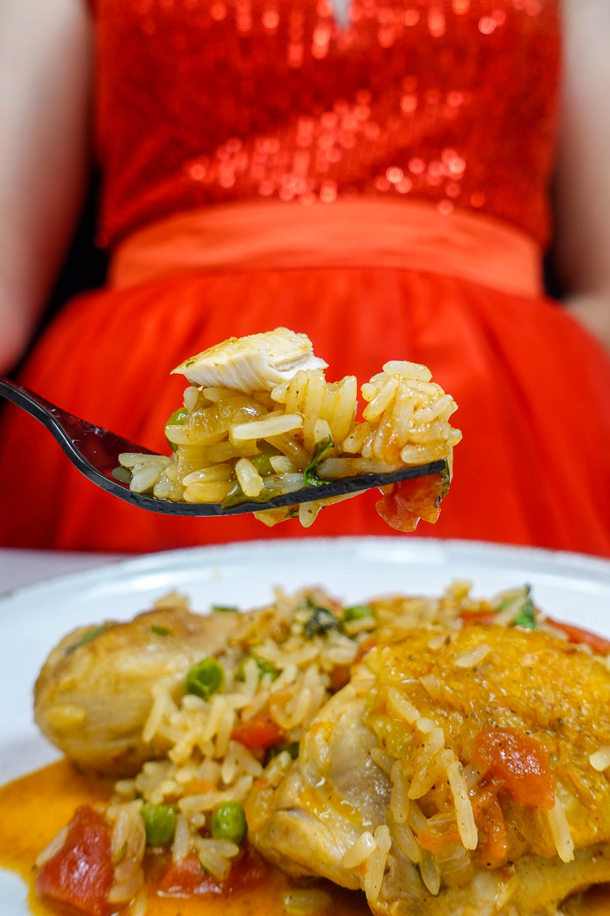 Forkful of Portuguese chicken rice with vegetables and chicken piece.