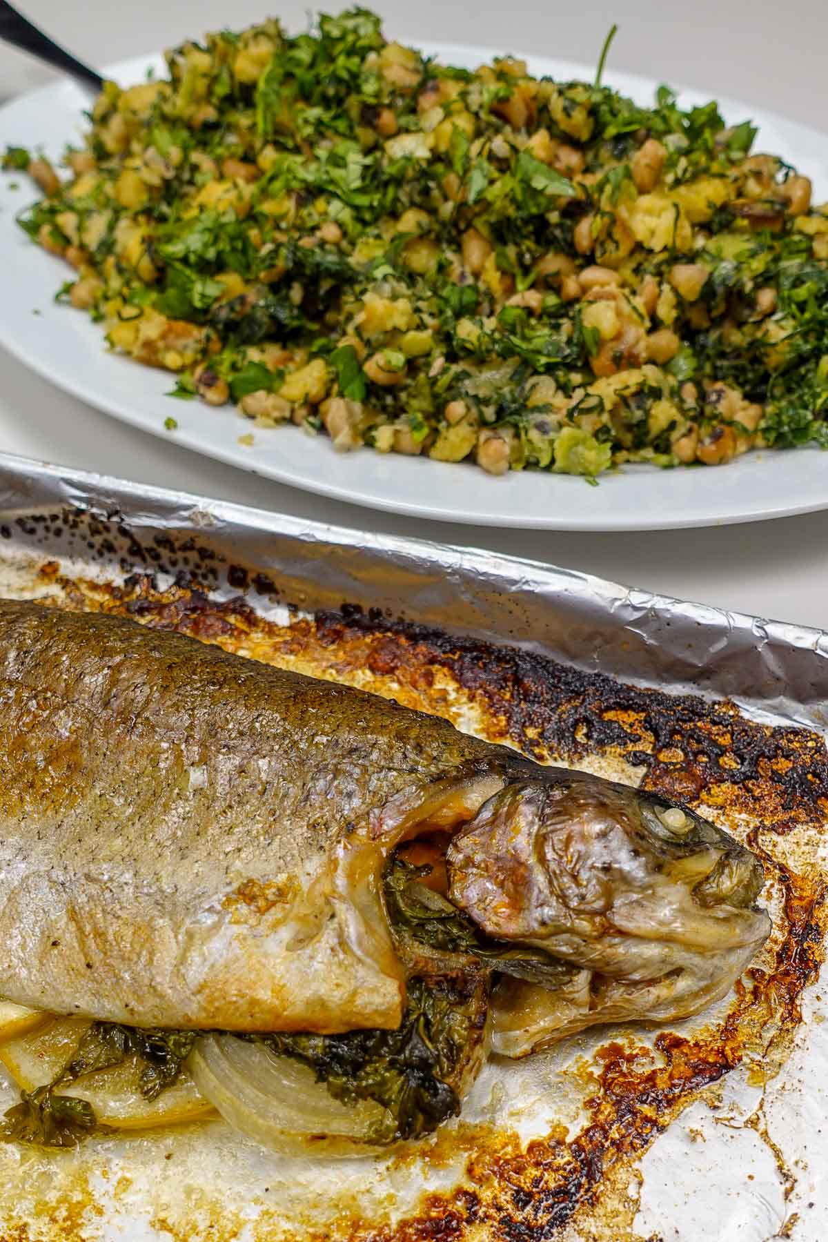 Baked whole rainbow trout with herbs and a side of seasoned beans and greens.