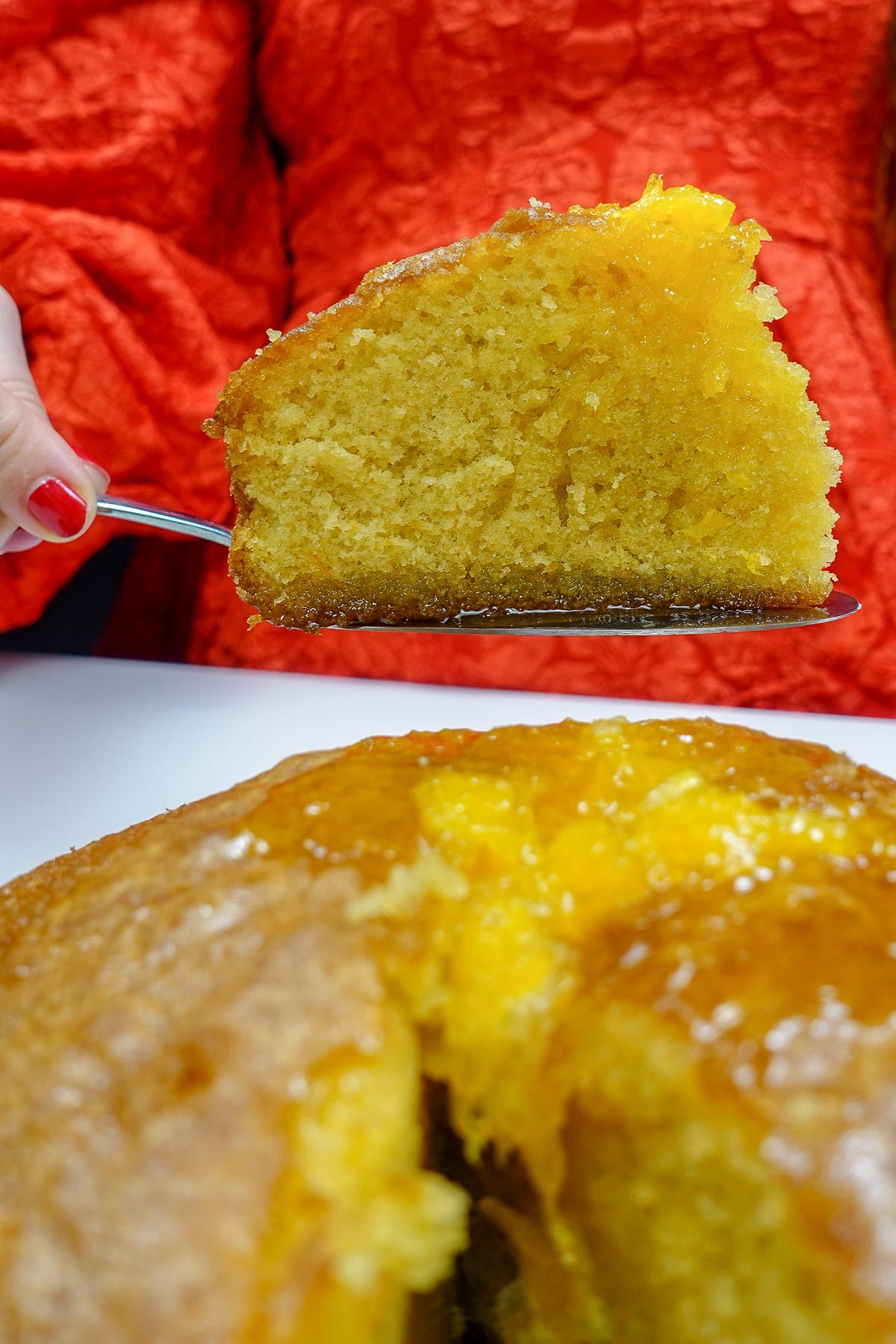 Slice of moist Portuguese orange cake with orange glaze on top.