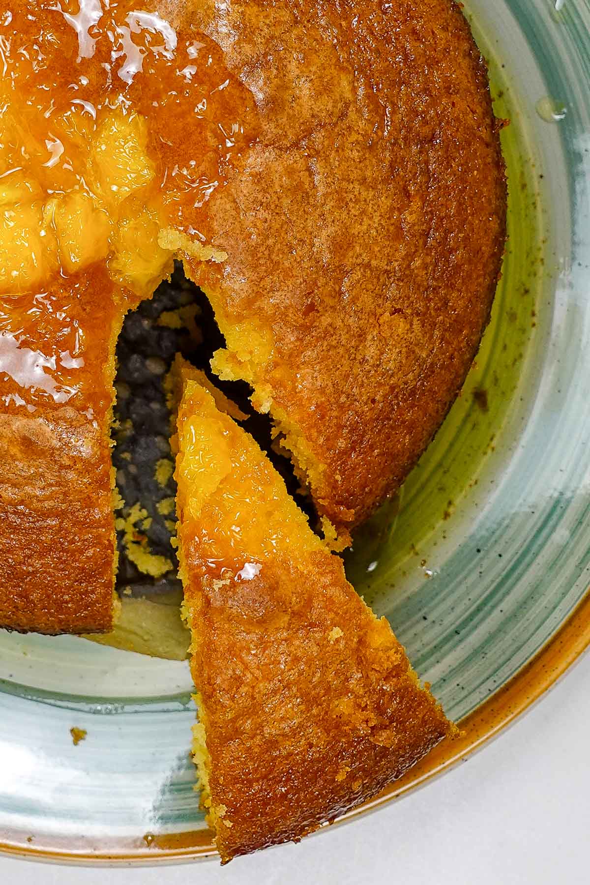 Moist Portuguese orange cake with a slice cut out on a ceramic plate.