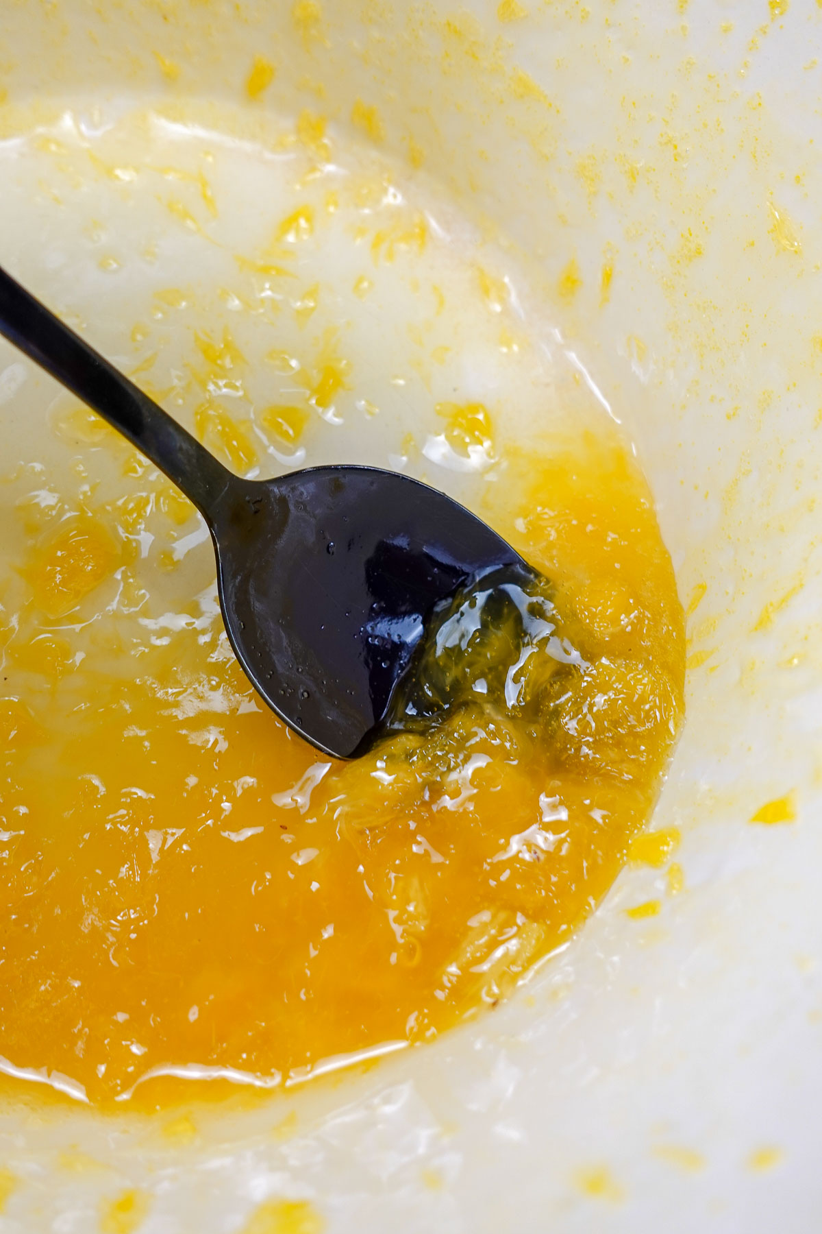 A pot with ready orange syrup and a spoon inside.