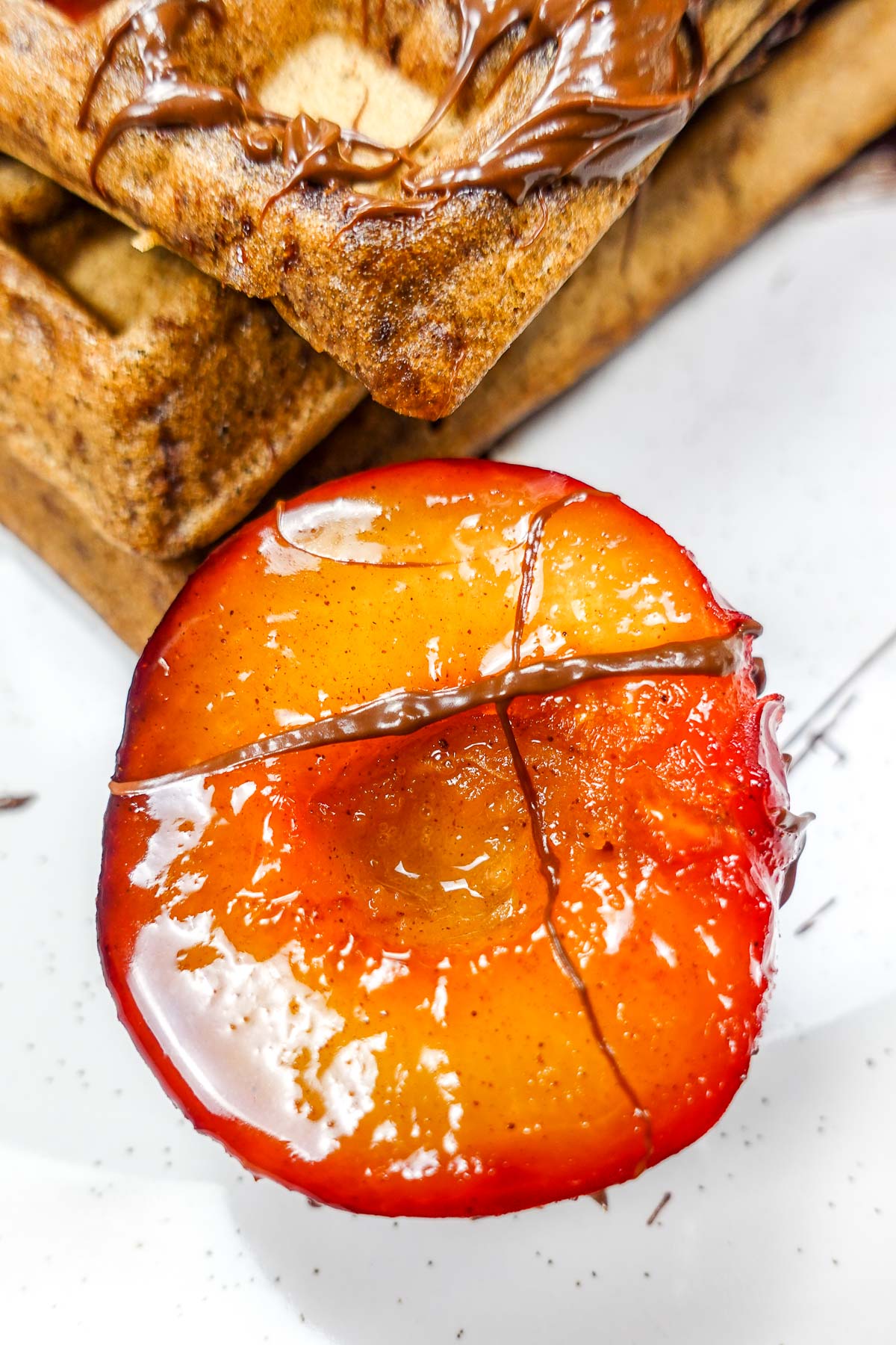 Caramelized plum half with chocolate drizzle and folded crepes.