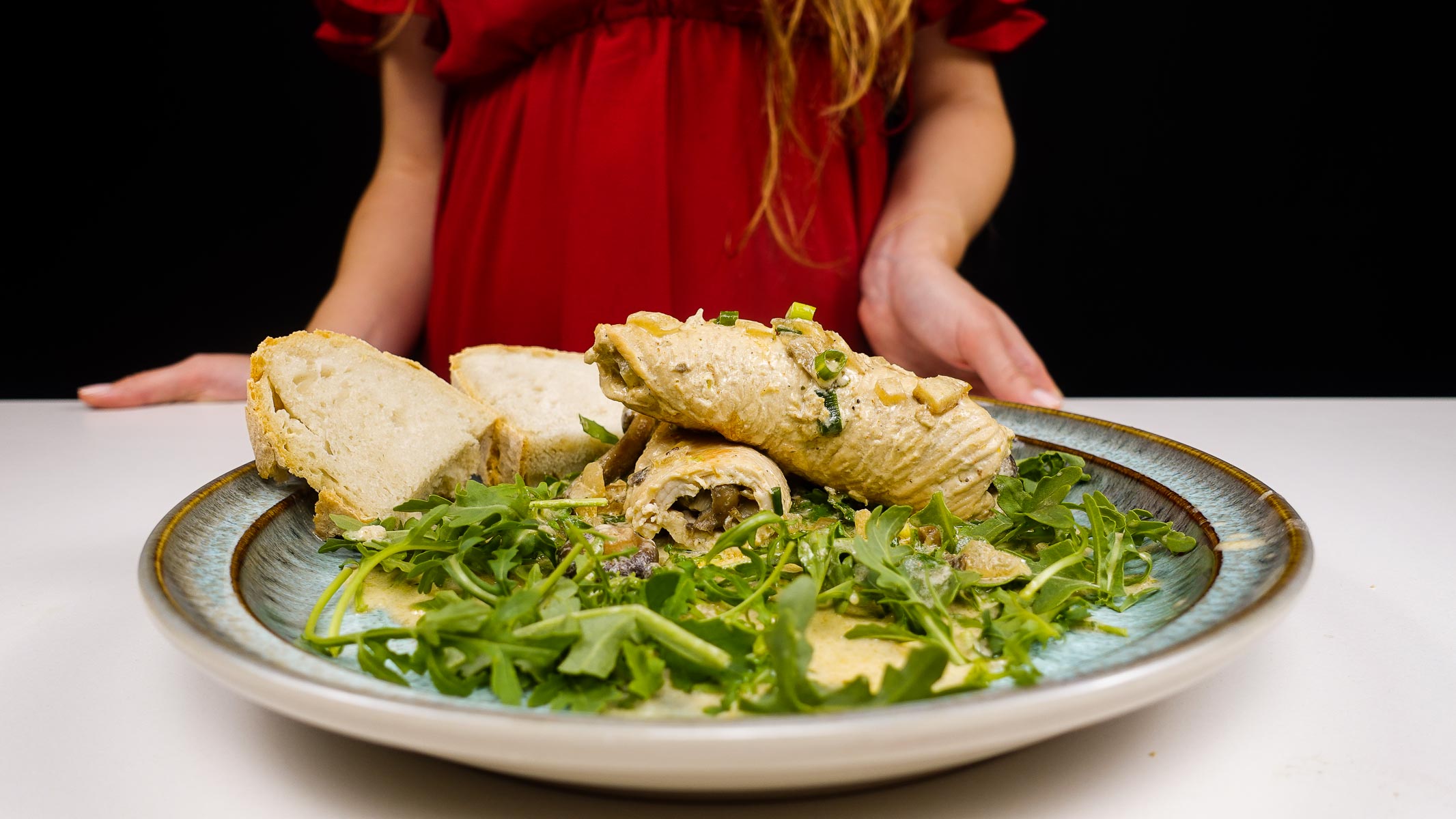 Turkey roulades with mushroom filling served with arugula and bread slices.