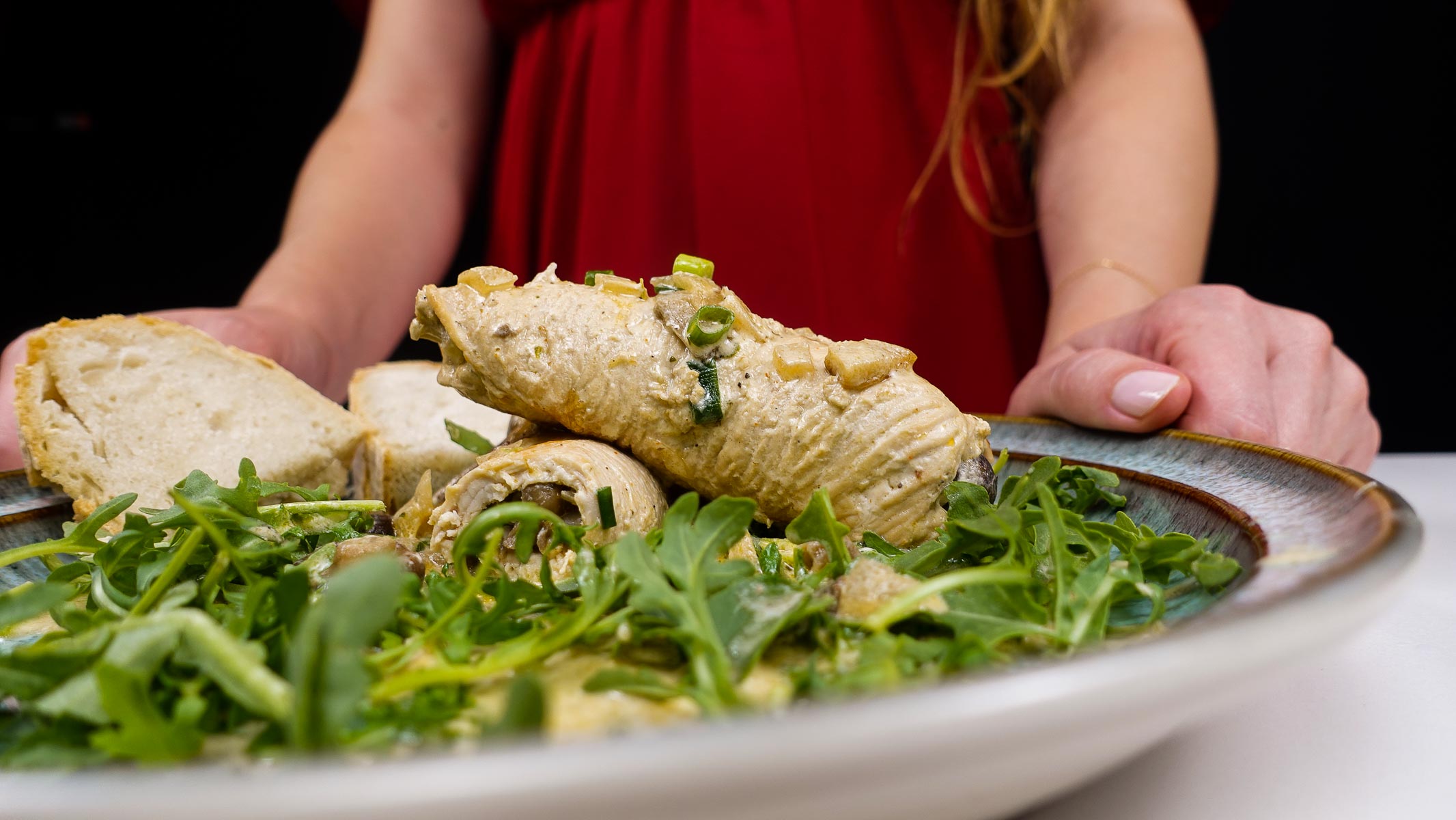 Turkey roulades with mushrooms served on arugula with bread slices.