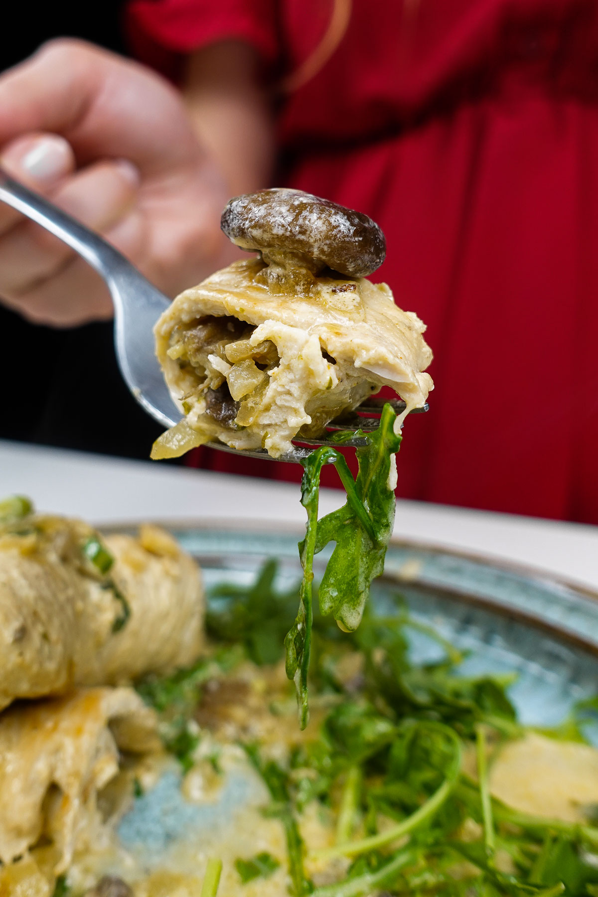 Fork holding turkey roulade with mushroom and greens.