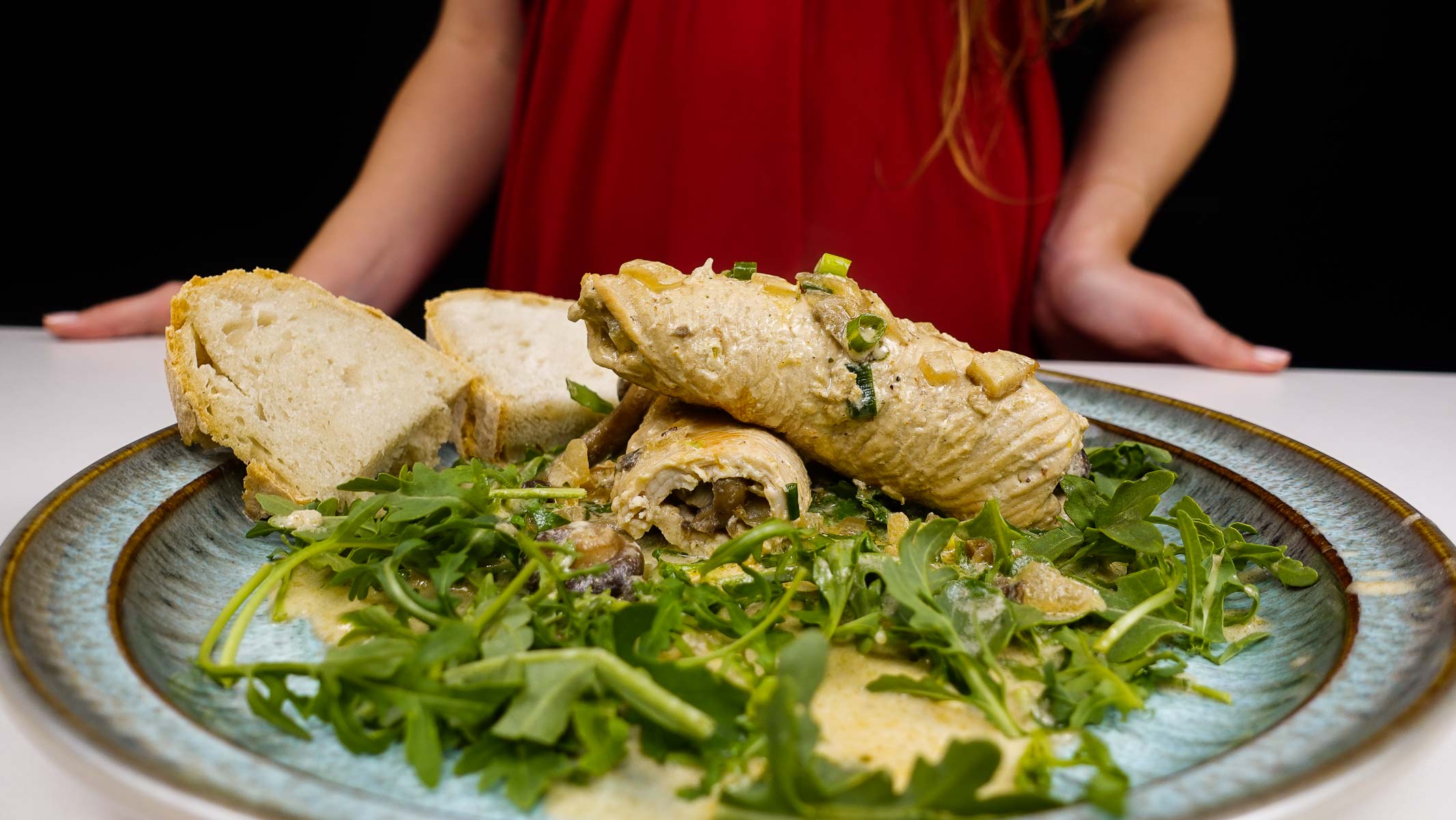 Turkey roulades stuffed with mushrooms served with fresh arugula and bread slices.