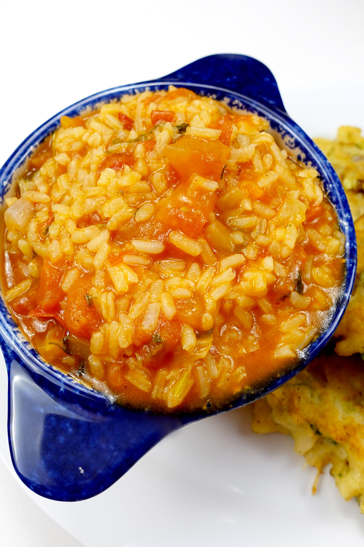 Bowl of Portuguese tomato rice beside cod cakes