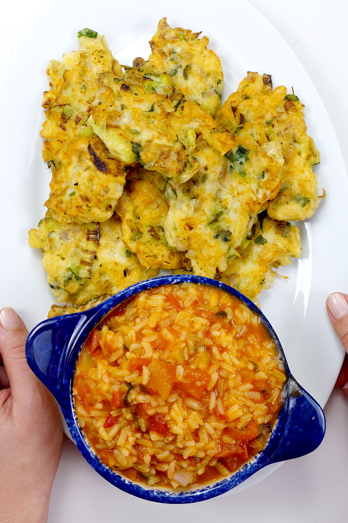 Tomato rice bowl held beside Portuguese cod cakes.