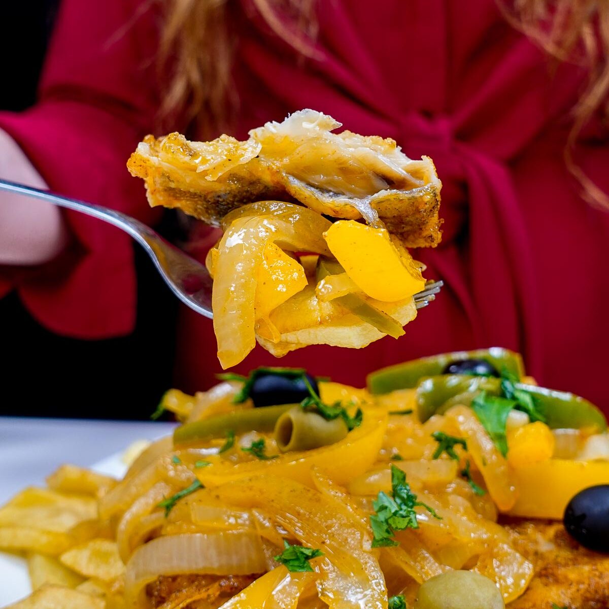 Crispy fried cod with sautéed onions, yellow peppers, olives, and potato fries.