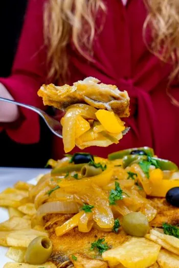 Crispy fried cod with sautéed onions, yellow peppers, olives, and potato fries.